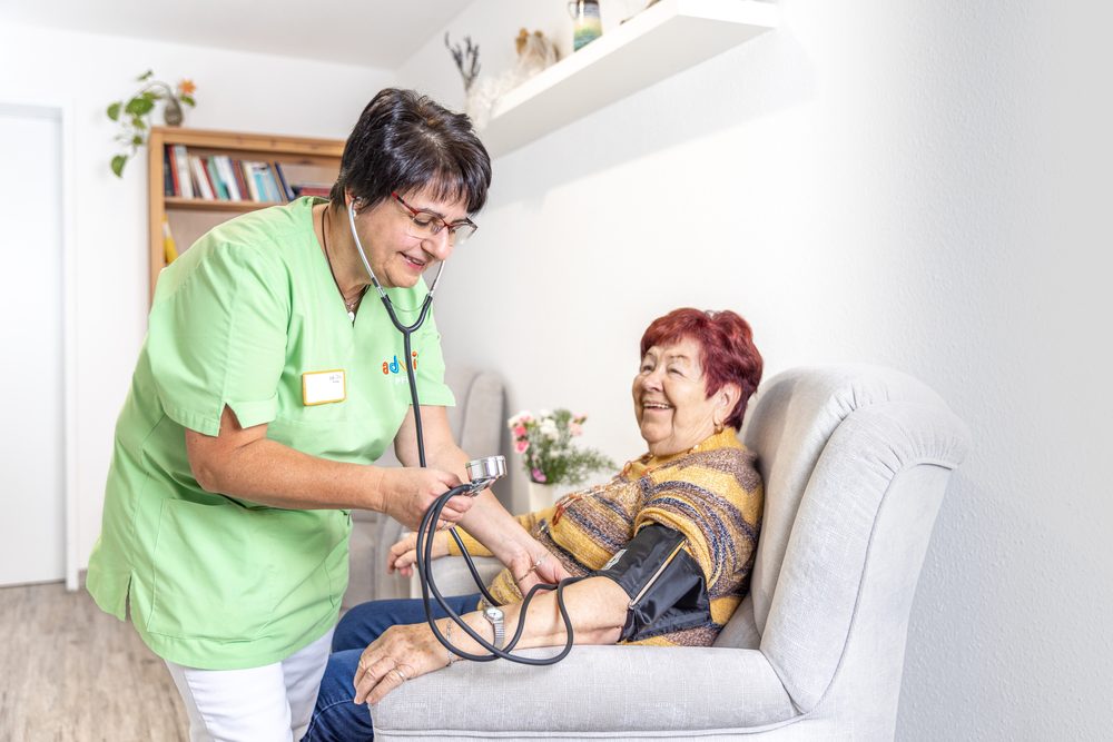 Pflegekraft misst den Blutdruck einer Bewohnerin